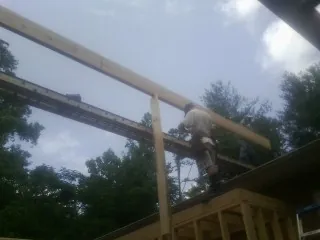 Carpenter setting a ridge beam over a new addition frame — Ice Dam Removal by Roofing Brothers in Carriere
