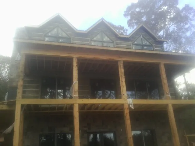 Dormers and porch framing on a large log home under construction — Roof Coating work by our crew in Carriere