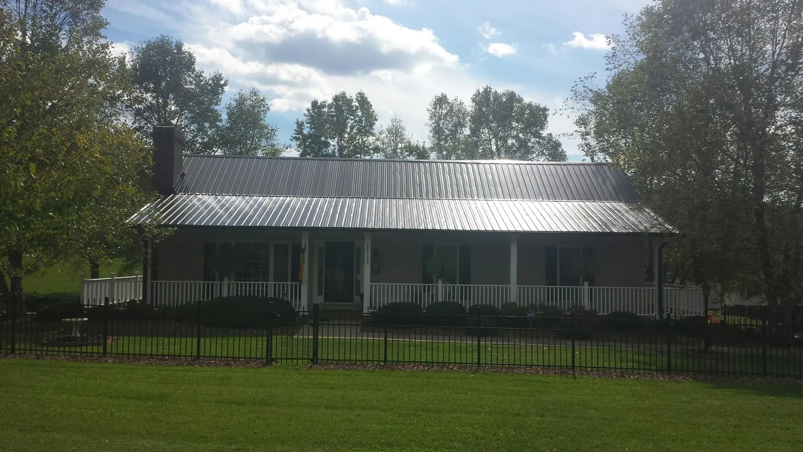 Gray metal roof on a brick ranch with a full width front porch — Gutter Guard Installation work by our crew in Carriere