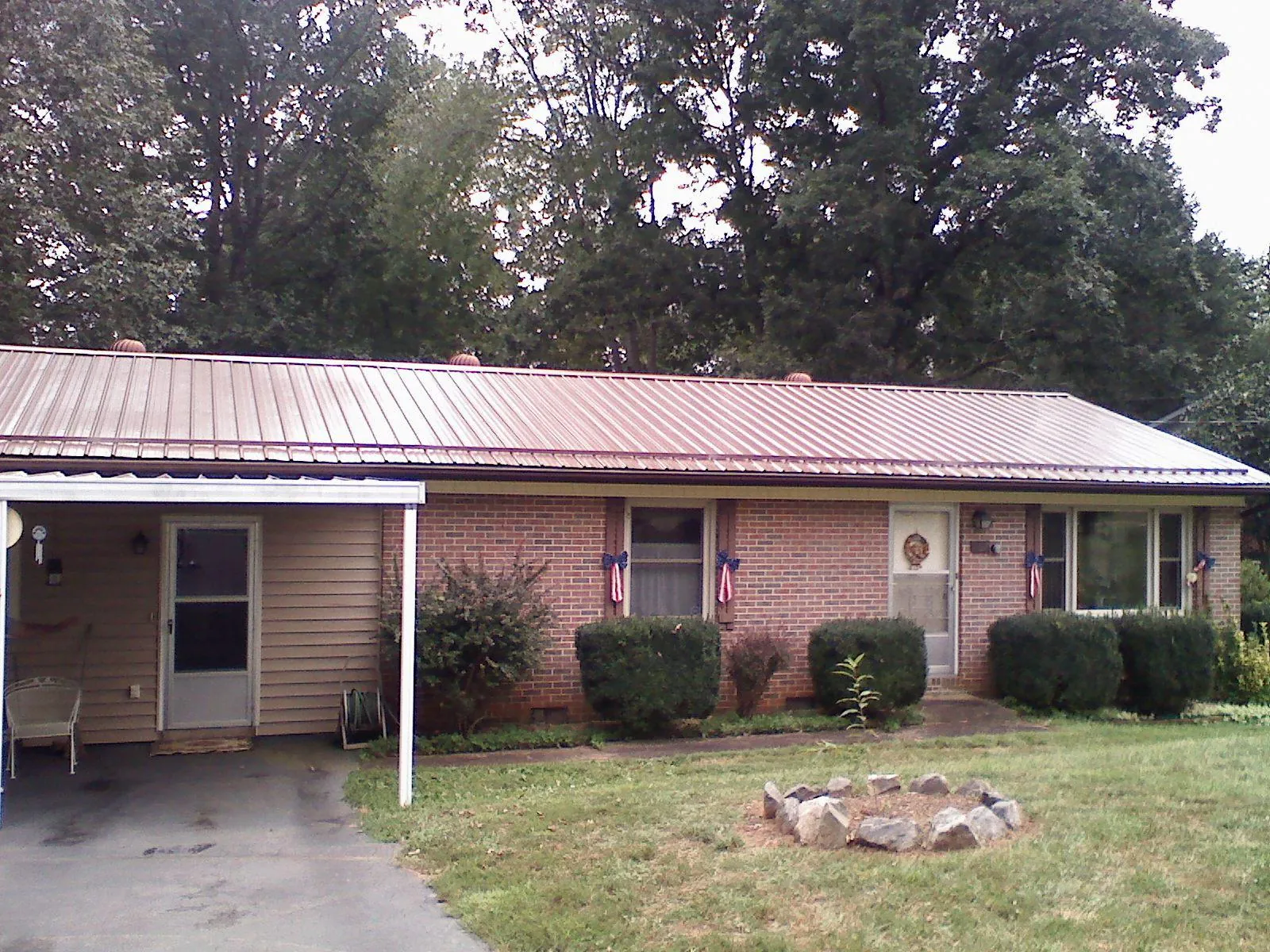 Bronze metal roof and carport on a brick ranch home — Roof Repair work by our crew in Carriere