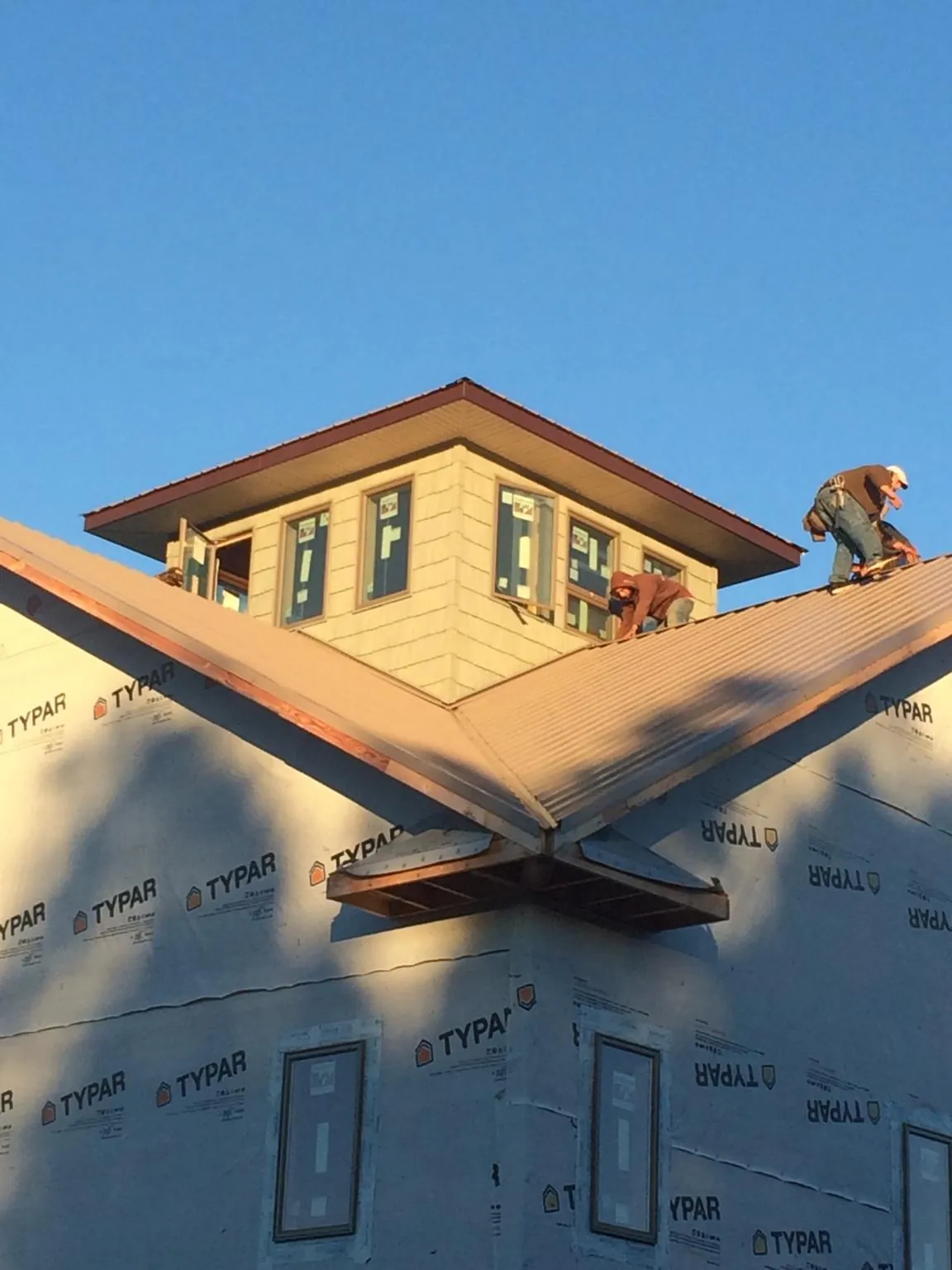 Roofers working around a rooftop cupola on a new metal roof at sunset — Roof Waterproofing in Carriere by Roofing Brothers